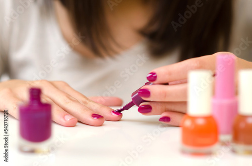 Young woman rasping and painting her nails at home