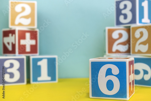 A cube with the number six on a blurry background with cubes with different numbers. Development. Layout for the School of mathematics