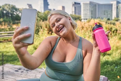 Portrait view of the full figured woman taking photo at the mobile phone
