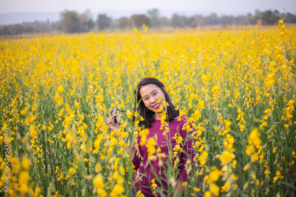Fototapeta premium Young woman in a field of yellow flowers
