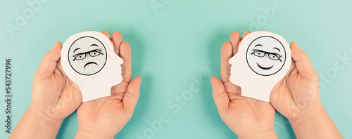 Fototapeta Naklejka Na Ścianę i Meble -  Holding a head with a sad and a happy face in the hands, mental health concept, positive and negative mindset, depression, support and evaluation symbol, emotion