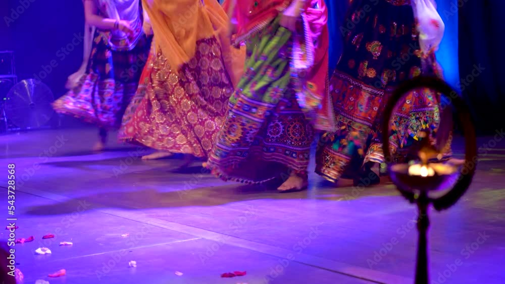Low angle shot of unidentified girls legs in traditional ghagra dress dancing to Indian classical music in front of a diya or candle, India dance, festival and celebration concept