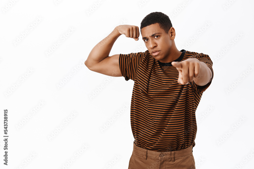 Sport and gym concept. Strong African american man flex biceps, shows muscles, looking confident, standing over white background Sport and gym concept. Strong African american man flex biceps, shows muscles, looking confident, standing over white background