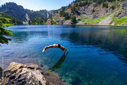 Fényképezés Adventurous athletic female hiker diving into an alpine lake in the Pacific Northwest