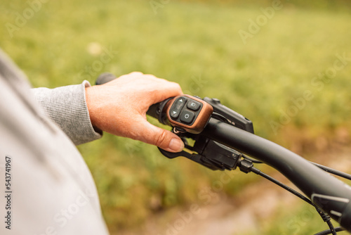 Woman hands with electric bike handlebar driving on an asphalt road in nature