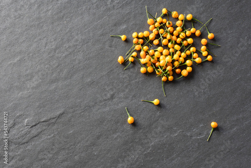 A group of yellow heirloom aji charapita peruvian peppers against a gray slate background