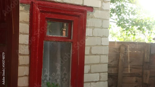 light rain against the sun against the background of the corner of the house and the red wooden window, a beautiful view