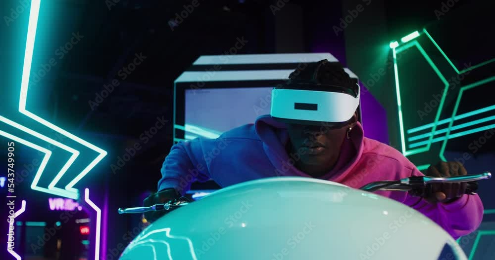Man wearing virtual reality glasses play online video game with motorbike simulator