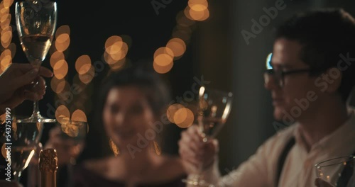 Close Up Multiracial young mans and womans wearing fashion wear clinking glasses with champagne, happy asian american and caucasian friends celebrating xmas, new year or birthday party indoors. PRORES