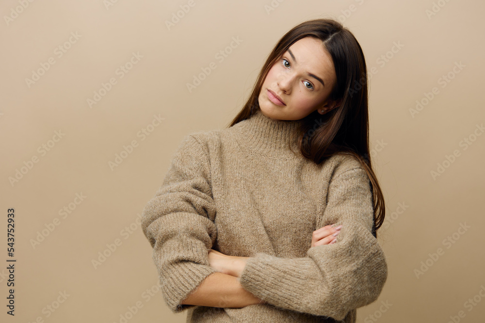 a relaxed, slightly upset woman stands in a stylish textured sweater, arms crossed over her chest and looks at the camera a relaxed, slightly upset woman stands in a stylish textured sweater, arms crossed over her chest and looks at the camera