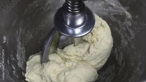 Raw dough in a bakery dough mixer. Bread making process by using flour mixing machine. Preparation of dough on home kitchen. Kneading the dough. The process of making a delicious treat or dessert.