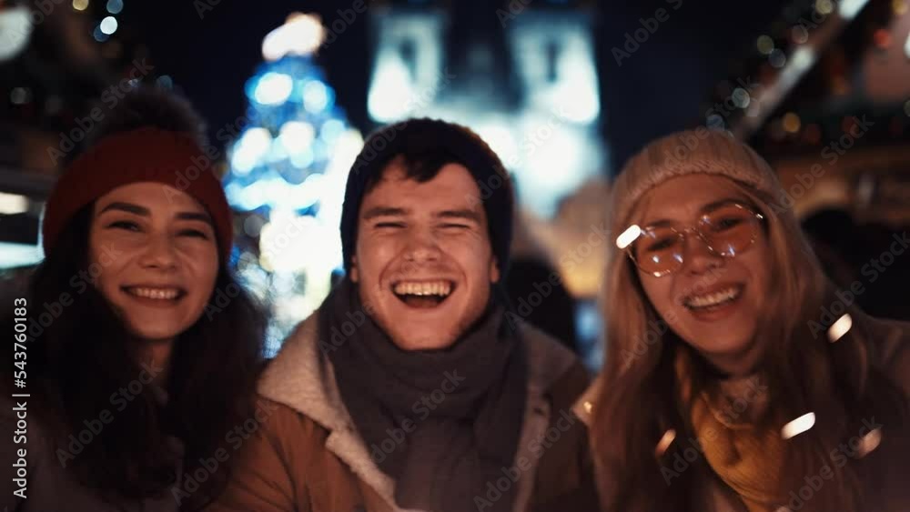 Three happy friends with sparklers on new year's eve in the middle of the street in the lights of the Christmas Tree. Concept for Christmas, New Year, Eve, Celebration, Friends, Family, Sparklers.