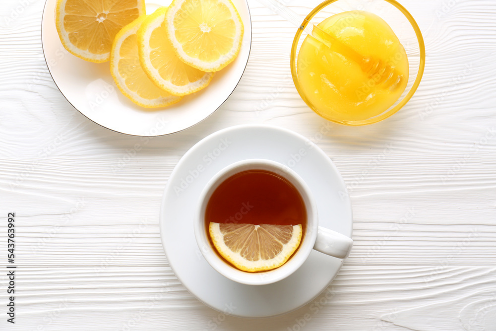 Cup with delicious immunity boosting tea, lemon and honey on white wooden table, flat lay Cup with delicious immunity boosting tea, lemon and honey on white wooden table, flat lay