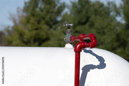 A red pipe with a valve on a gas tank