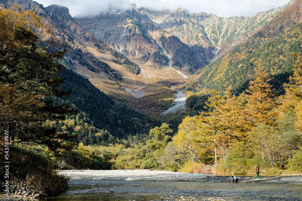 Fototapeta premium Beautiful background of the center of Kamikochi national park by snow mountains, rocks, and Azusa rivers from hills covered with leaf change color during the Fall Foliage season.