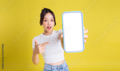 Φωτογραφία Young Asian woman holding phone with cheerful face on yellow background