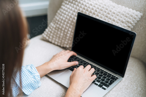 Crop photo of young woman working on laptop sitting on carpet at home