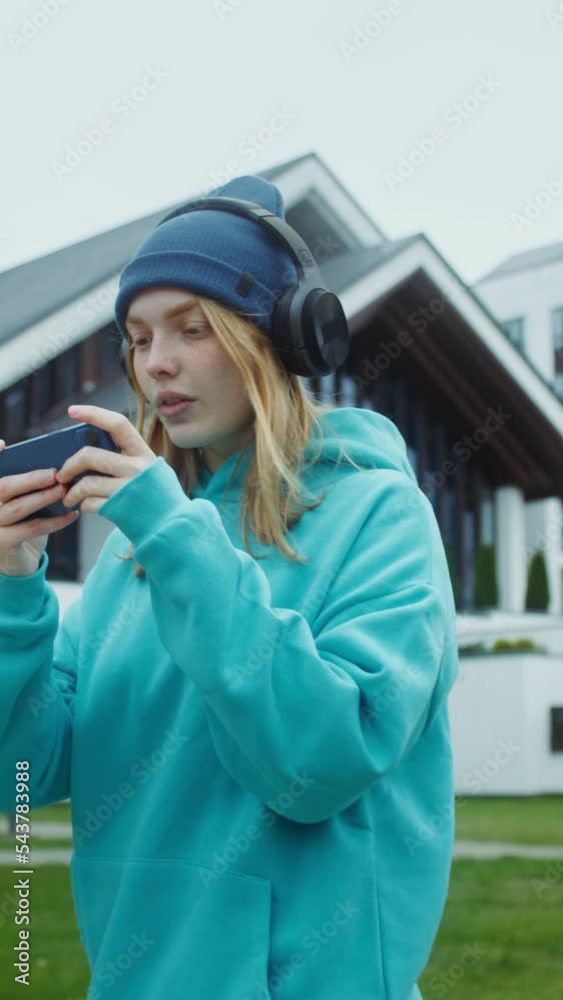 Woman playing online game on mobile phone while walking on the street