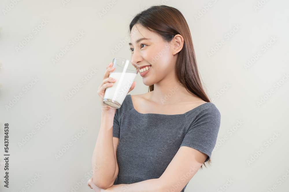 Happy, asian young woman, girl drinking a glass of white fresh, warm or hot dairy milk for calcium, vitamin wholesome good nutrition in morning. lifestyle, product healthy people, Isolated background. Happy, asian young woman, girl drinking a glass of white fresh, warm or hot dairy milk for calcium, vitamin wholesome good nutrition in morning. lifestyle, product healthy people, Isolated background.