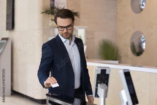 Quadro em tela Young 35s businessman in elegant formal suit using pass card to open entrance automatic gates inside modern office building