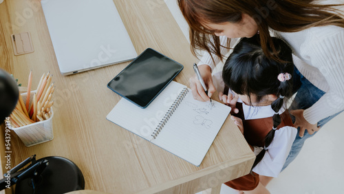 Young asian mother teaching holding little kid girl daughter hand writing drawing book, Education learning concept at home