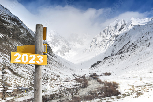  2023 written on yellow postsign  on mountain in snow background photo