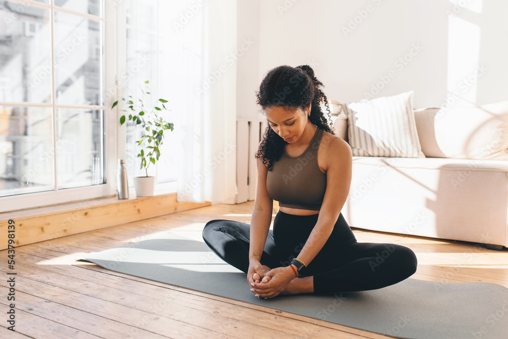Active african american pregnant woman practicing yoga, sitting in butterfly or konasana pose, stretching muscles on mat, doing prenatal exercises for healthy pregnancy and prepare body for childbirth Active african american pregnant woman practicing yoga, sitting in butterfly or konasana pose, stretching muscles on mat, doing prenatal exercises for healthy pregnancy and prepare body for childbirth