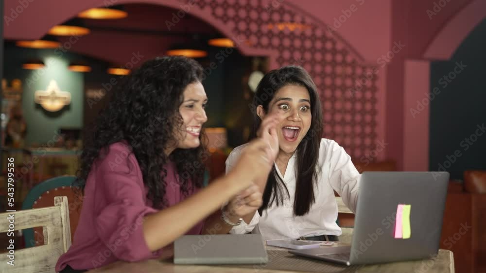 Excited Two happy Indian business woman celebrate corporate success look at laptop applaud engaged in professional victory great teamwork result read good news online startup win in cafe. Excited Two happy Indian business woman celebrate corporate success look at laptop applaud engaged in professional victory great teamwork result read good news online startup win in cafe.