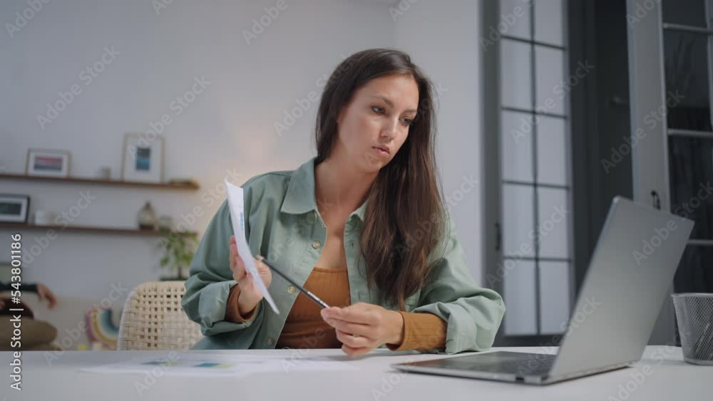 A young hispanic woman works at home in the living room while her family plays and has fun, holds a presentation of the project to her business partners or shows the results of startup calculations