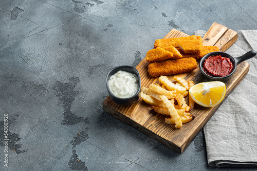 Fried fish finger stick or french fries fish with sauce, on wooden cutting board, on gray background , with copyspace  and space for text