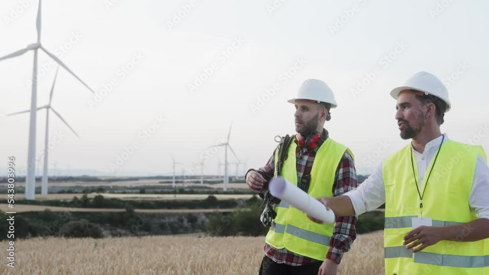 Electrical engineers and technicians walking outdoors around electricity wind turbine, innovation for renewable energy ecology project 