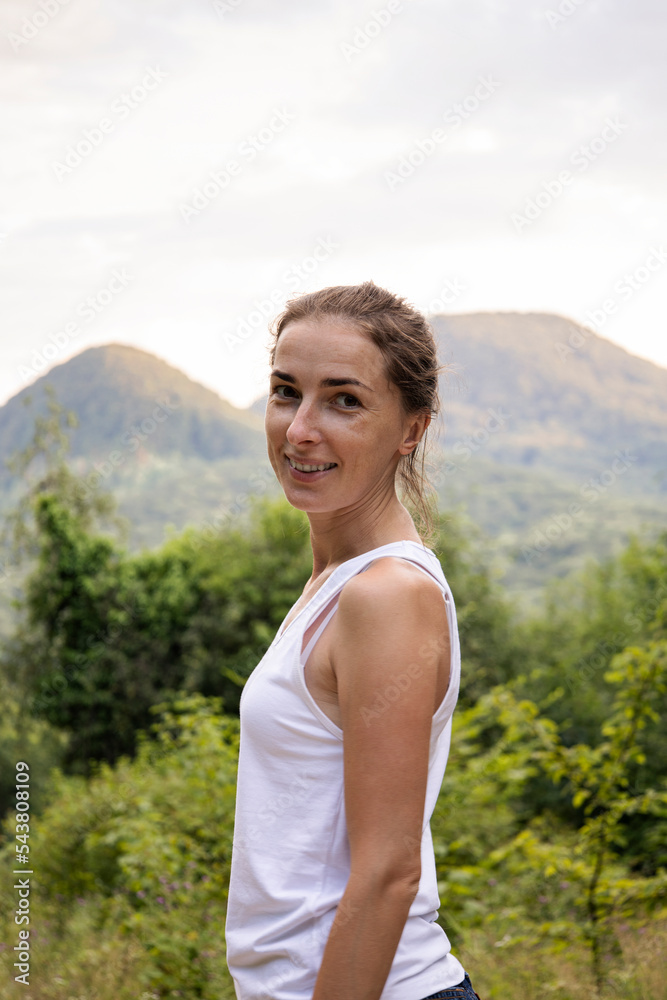 Obraz premium Smiling young woman in the forest against the backdrop of mountains