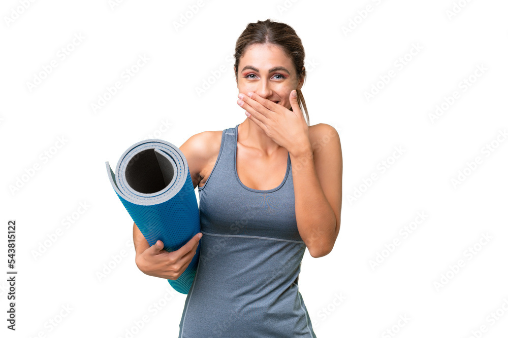 Pretty Young Uruguayan sport woman going to yoga classes while holding a mat over isolated background happy and smiling covering mouth with hand