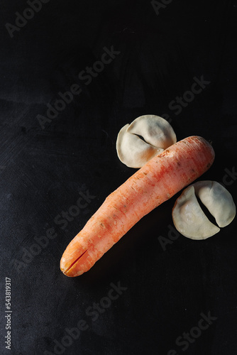 Carrots and dumplings on a black background. Silhouette of a dick