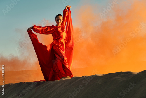 Woman in red dress dancing in the desert