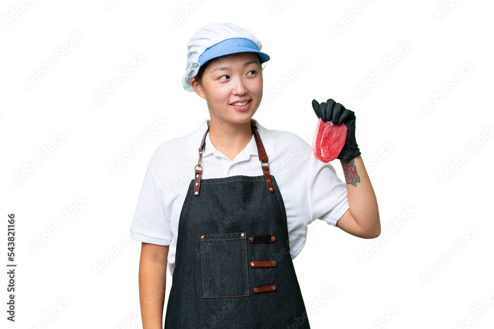 Young caucasian woman wearing an apron and serving fresh cut meat over isolated background looking to the side and smiling Young caucasian woman wearing an apron and serving fresh cut meat over isolated background looking to the side and smiling