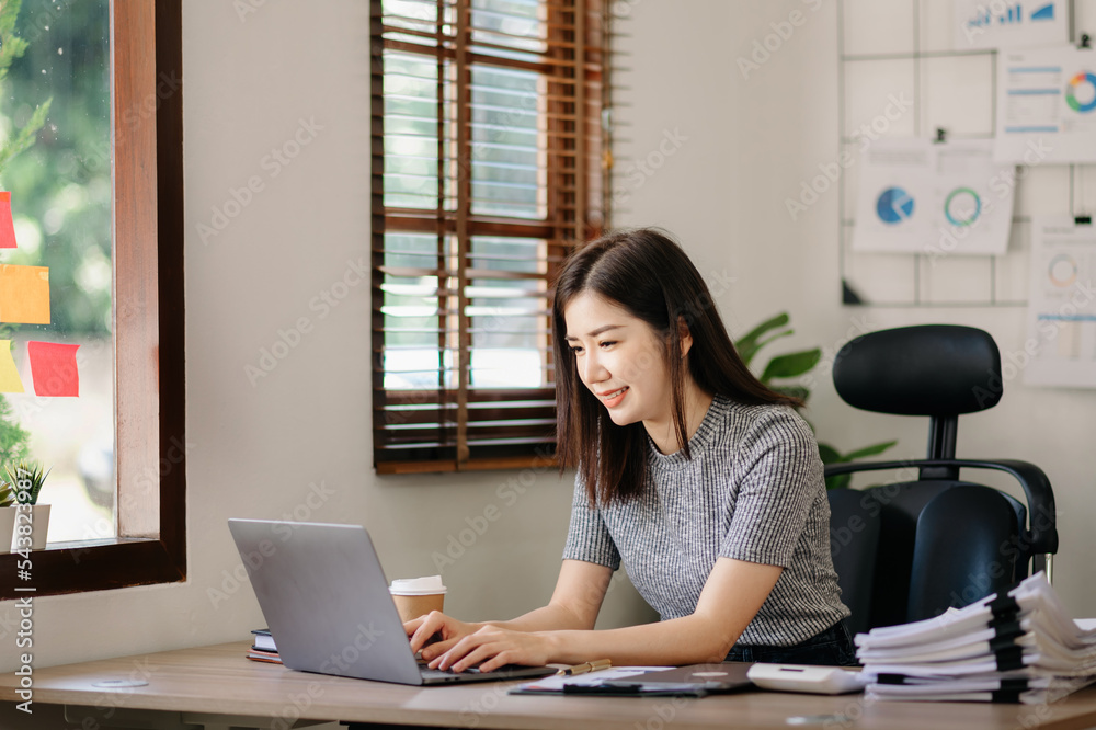 Beautiful Asian business woman typing laptop and tablet Placed at the table at the office Beautiful Asian business woman typing laptop and tablet Placed at the table at the office