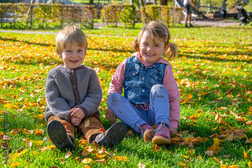 Young Children - boy and girl - playing in the park in autumn having fun