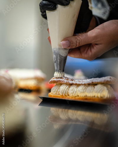 Une pâtissière prépare un éclair à la crème dans une pâtisserie 