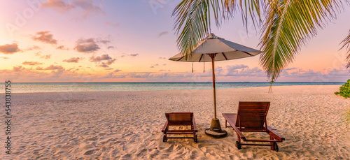Beautiful panoramic nature. Tropical beach sunset as summer island landscape with chairs umbrella palm leaves calm sea shore, coast. Luxury travel panoramic destination banner for vacation or holiday  © icemanphotos