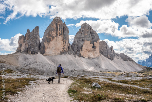 A female person hiking lonely with her dog around the Drei Zinnen mountains, the Dolomites in South Tirol