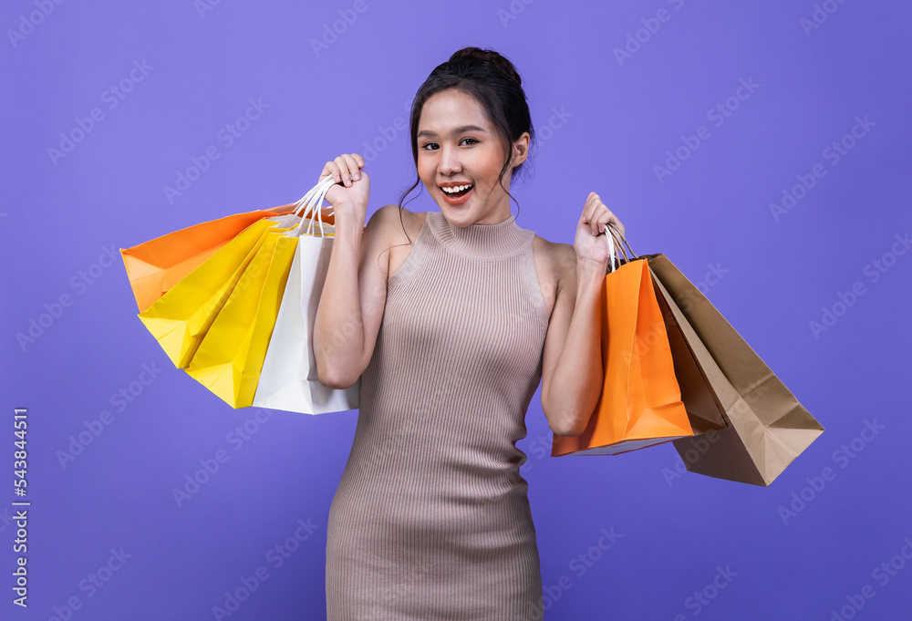 Asian young beautiful women are using smart phone shopping online with a shopping bag isolated in violet color background with copy space. Asian young beautiful women are using smart phone shopping online with a shopping bag isolated in violet color background with copy space.