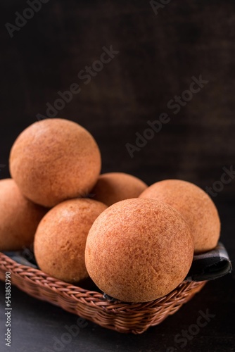Beautiful shot of round Colombian tradition food bunuelo on wooden plate isolated on dark background photo