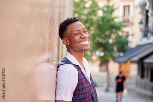 handsome african-american man showing white teeth leaning against the wall