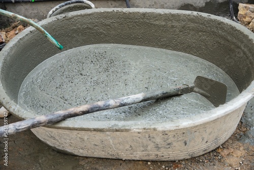 builder contractor man job mix concrete in industry work project, pouring pipe water into the big mixing tray in construction site as professional employment