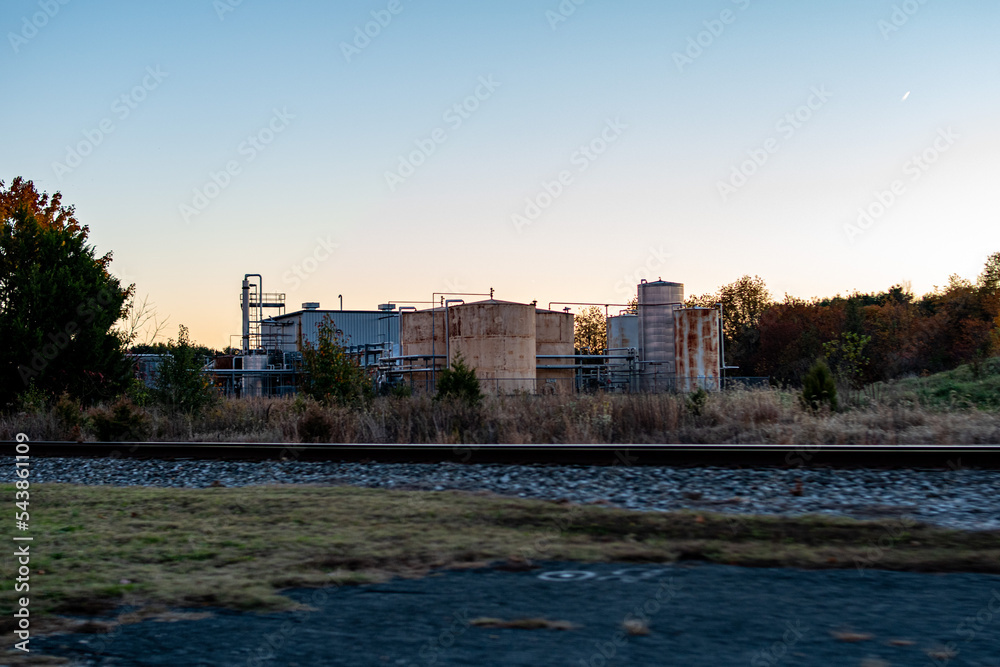 Fototapeta premium Sunset over industrial plant and rail road tracks