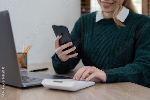 Close up Business woman using calculator and phone for do math finance on wooden desk in office and business working background, tax, accounting, statistics and analytic research concept