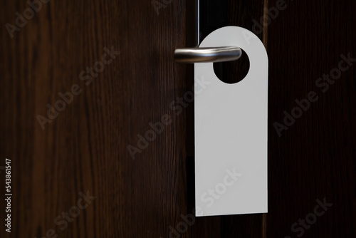 Door knob with blank door hanger mock-up. An empty white flyer mockup hangs on the door handle. Leaflet design. Don't disturb the sign. Hotel room clear hanger. Do not disturb the signal.
