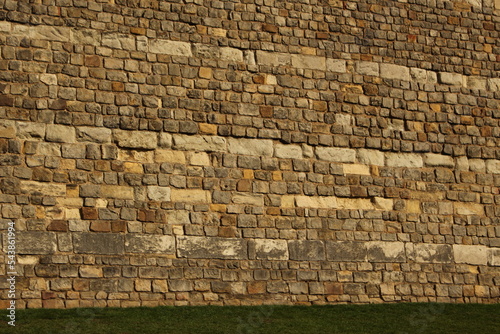 Old stone castle wall backdrop with small sliver of grass on the bottom. Beige and grey stone wall texture with copy, text space. Outer wall of Windsor Castle, medieval old british stone fortress wall photo