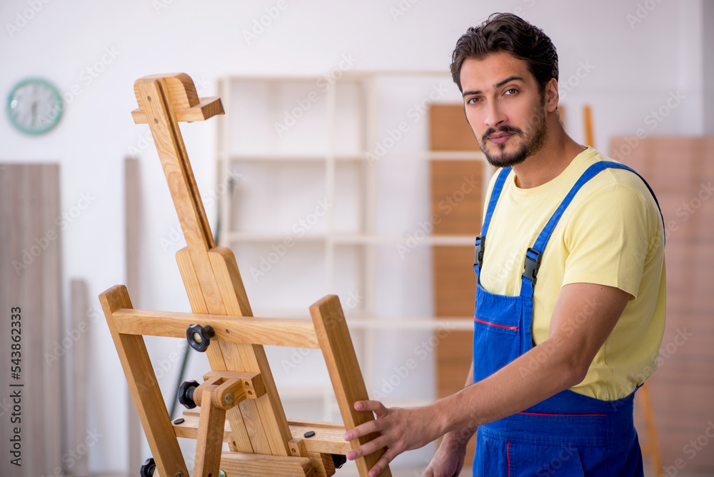 Young male repairman repairing easel at home Young male repairman repairing easel at home